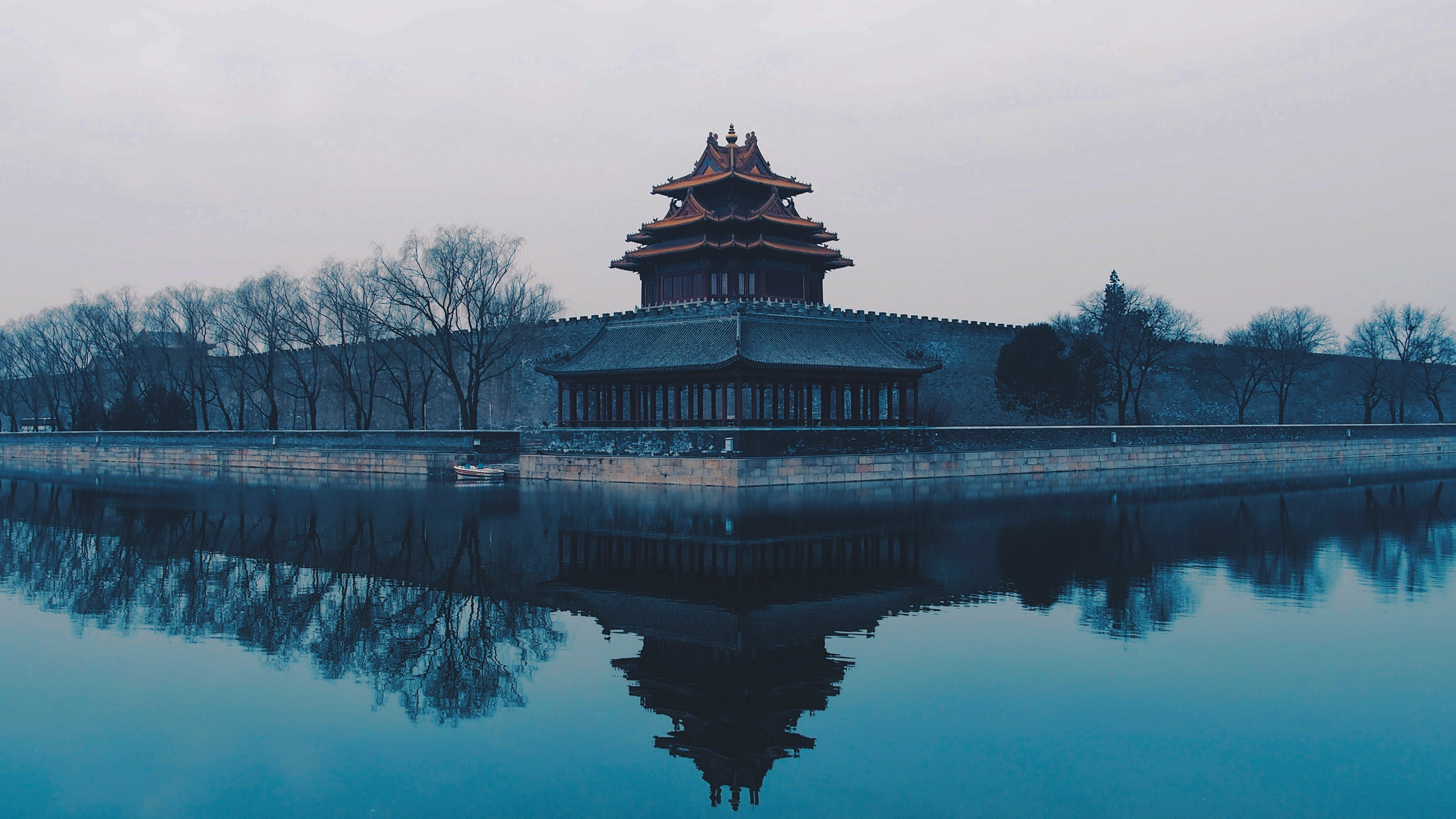 Misty view of a traditional Chinese watchtower beside water, reflected in the surface. Credit photo:Rita Chou/Unsplash