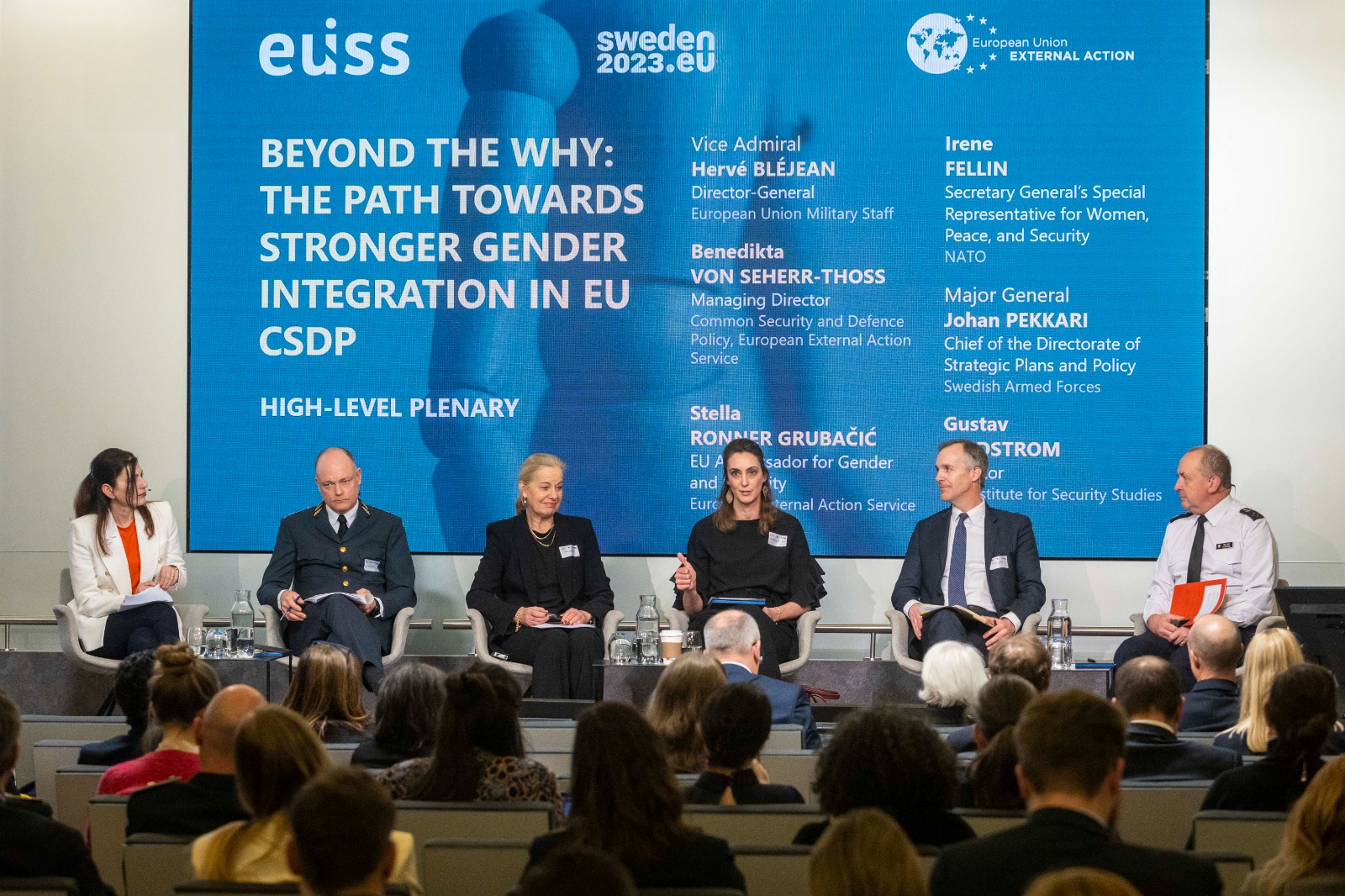 Panel members on a stage with background displaying the theme of the seminar ©EUISS