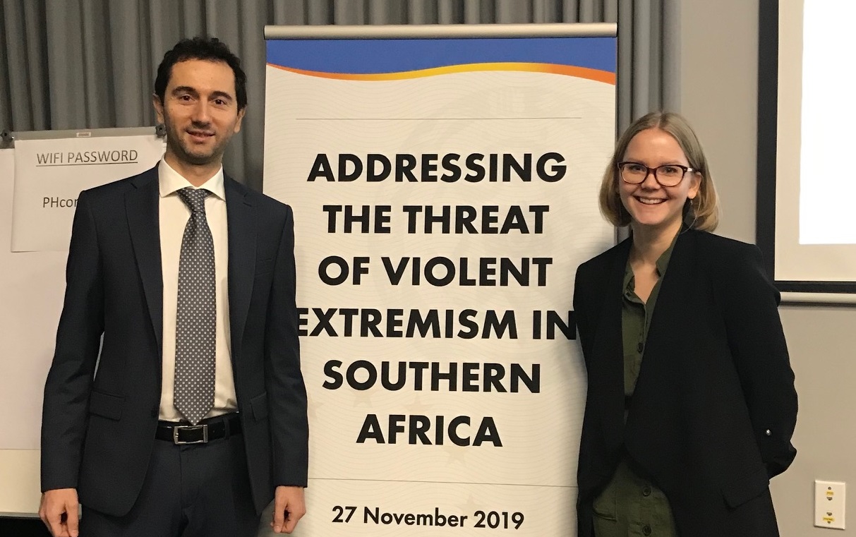 Two EU Analysts in front of event banner