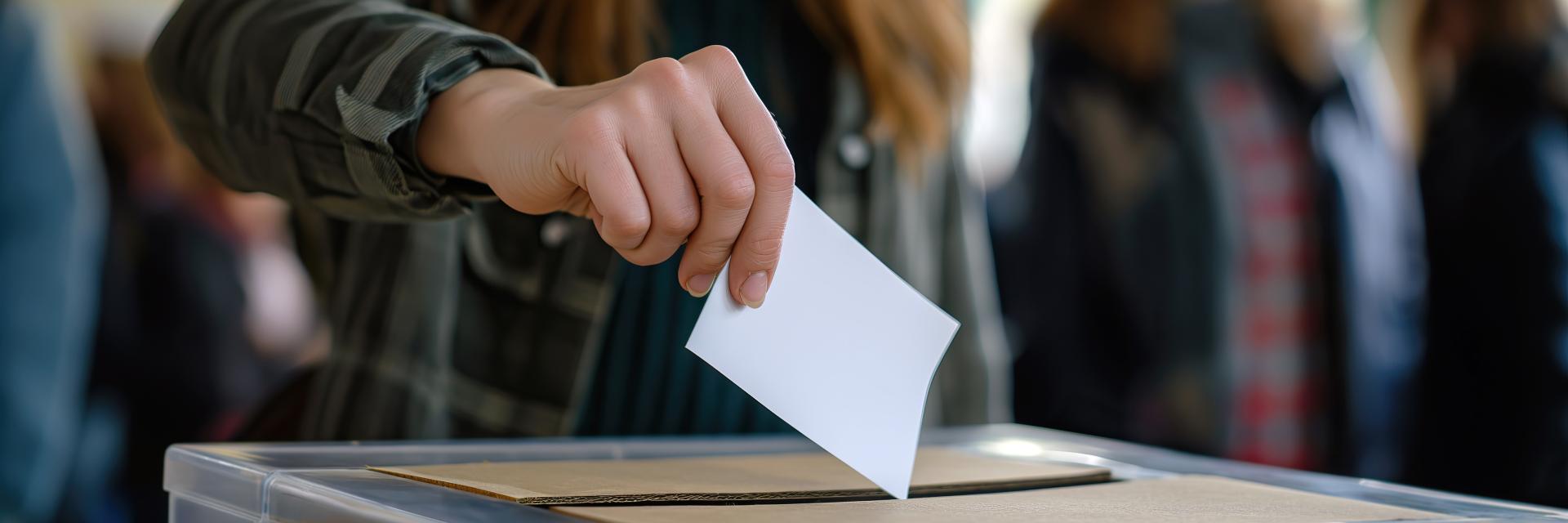 Person Depositing Voting Card Into Ballot Box. Credit: Envato