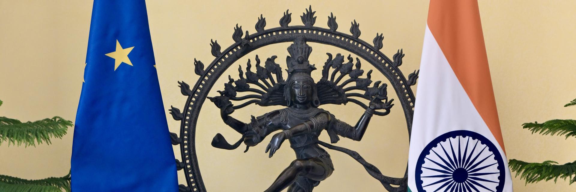 A statue of Shiva as Nataraja stands between the European Union flag and the Indian national flag indoors. Image credit: European Union, 2025