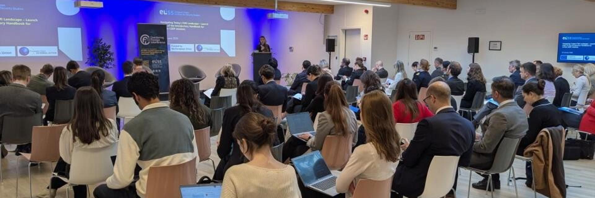 Guest to event sitting in room looking at the stage. Credit photo: EUISS