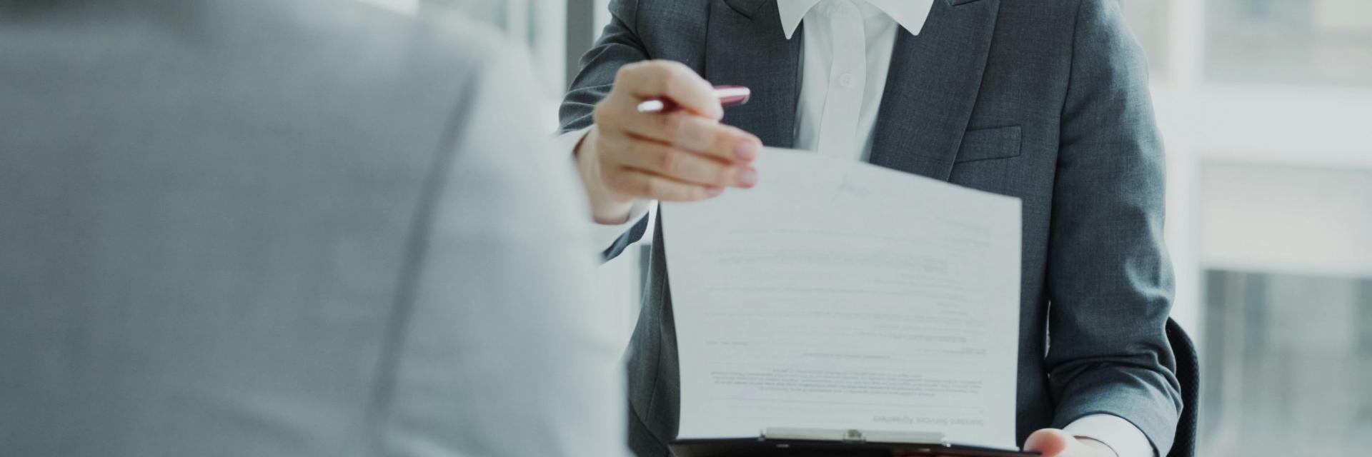 HR businesswoman having job interview with young man in suit and watching his resume application in modern office indoors | © Vitaly Gariev