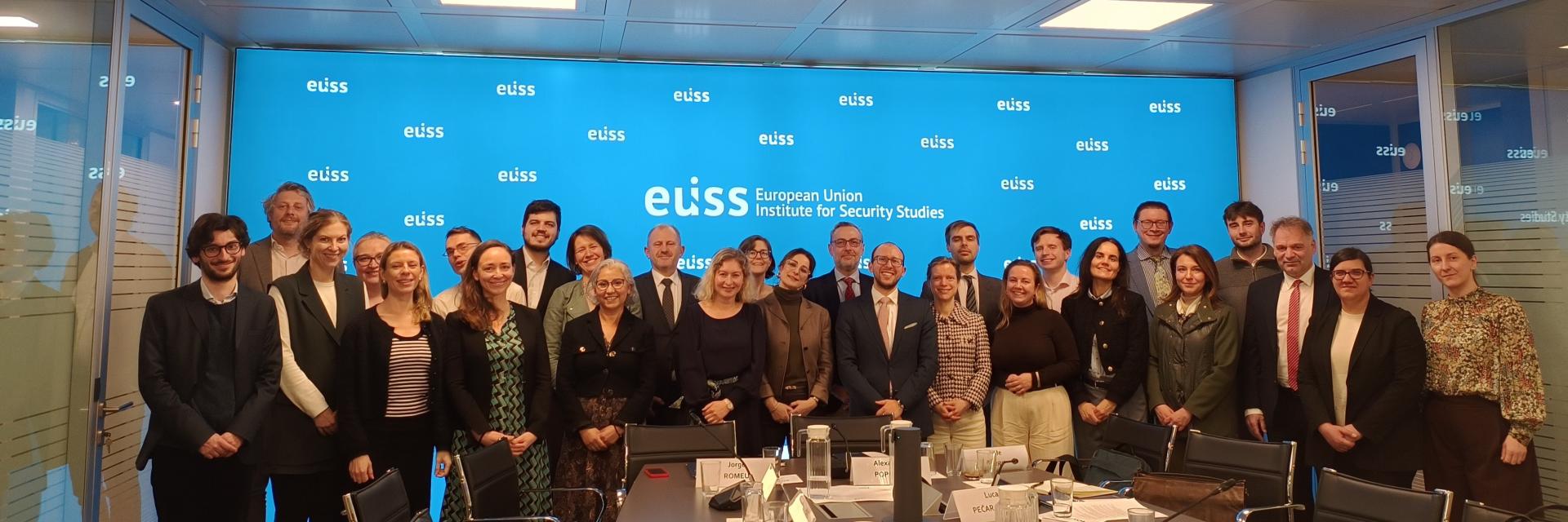 Group posing for photo in a meeting room in front of a background with EUISS logo. Credit photo: EUISS