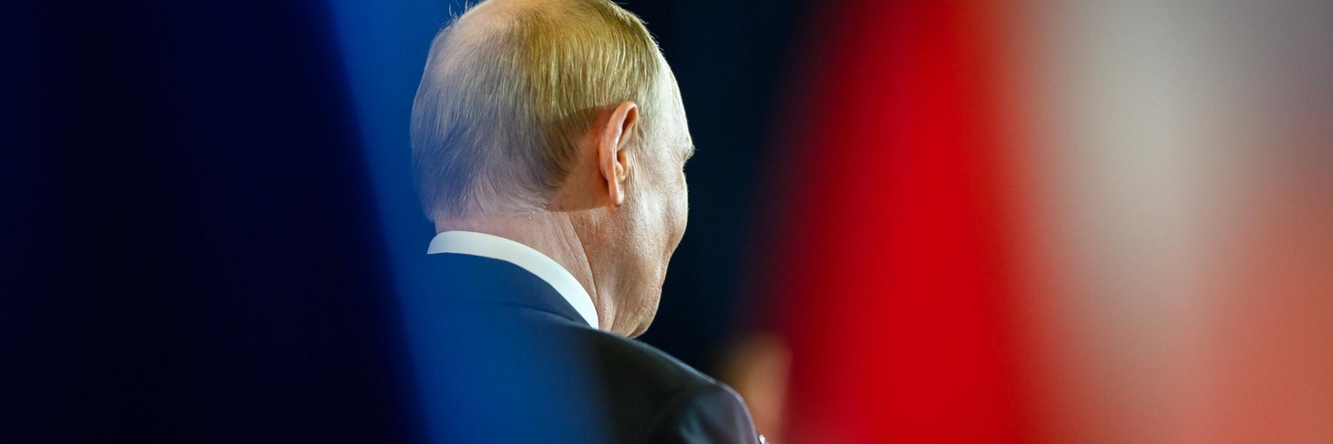 Rear view of Vladimir Putin in a dark suit speaking on stage. Credit photo: Official White House Photo by Daniel Torok