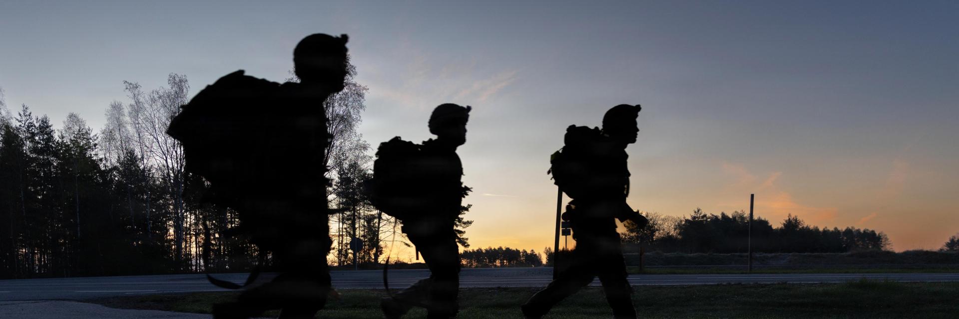Silhouettes of soldiers walking as sun is setting. Credit photo: Army Pfc. Kadence Connors, US department of war. The appearance of US Department of War visual information does not imply or constitute DoW endorsement