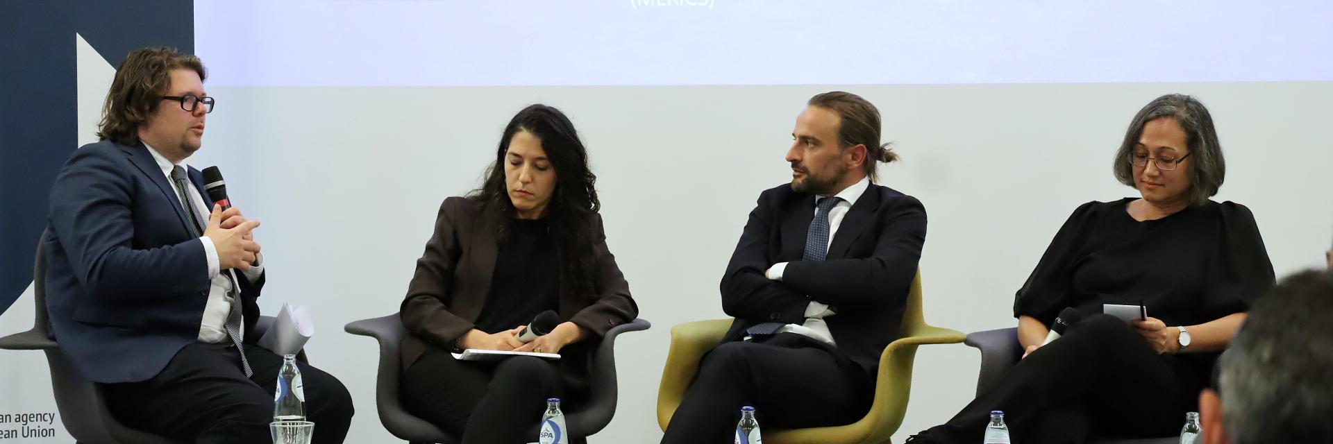 2 women and 2 men sitting on stage. One man is speaking on a microphone. Credit photo: EUISS 