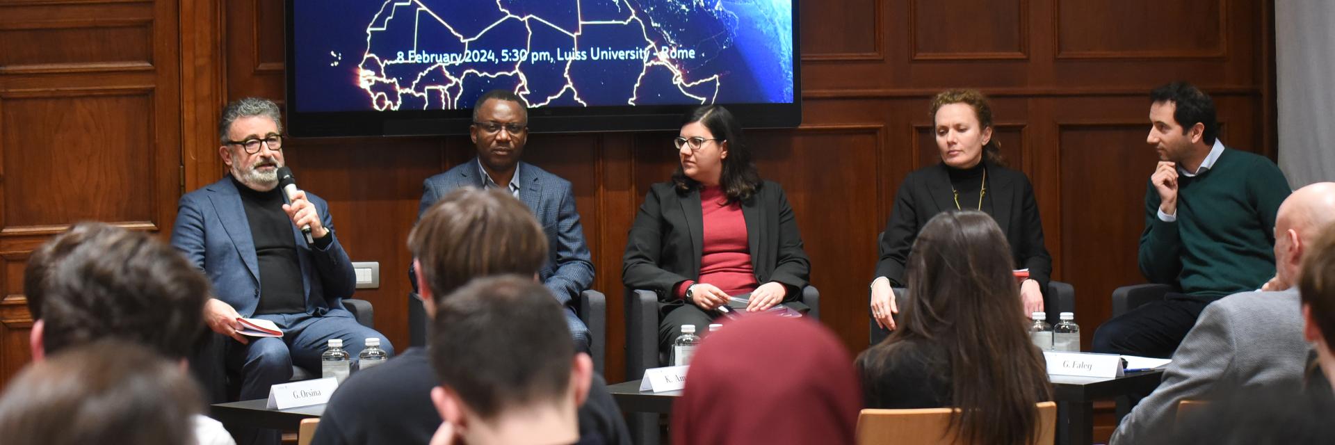 Speakers of the event (3 men, 2 women) sitting in front of an audience © LUISS