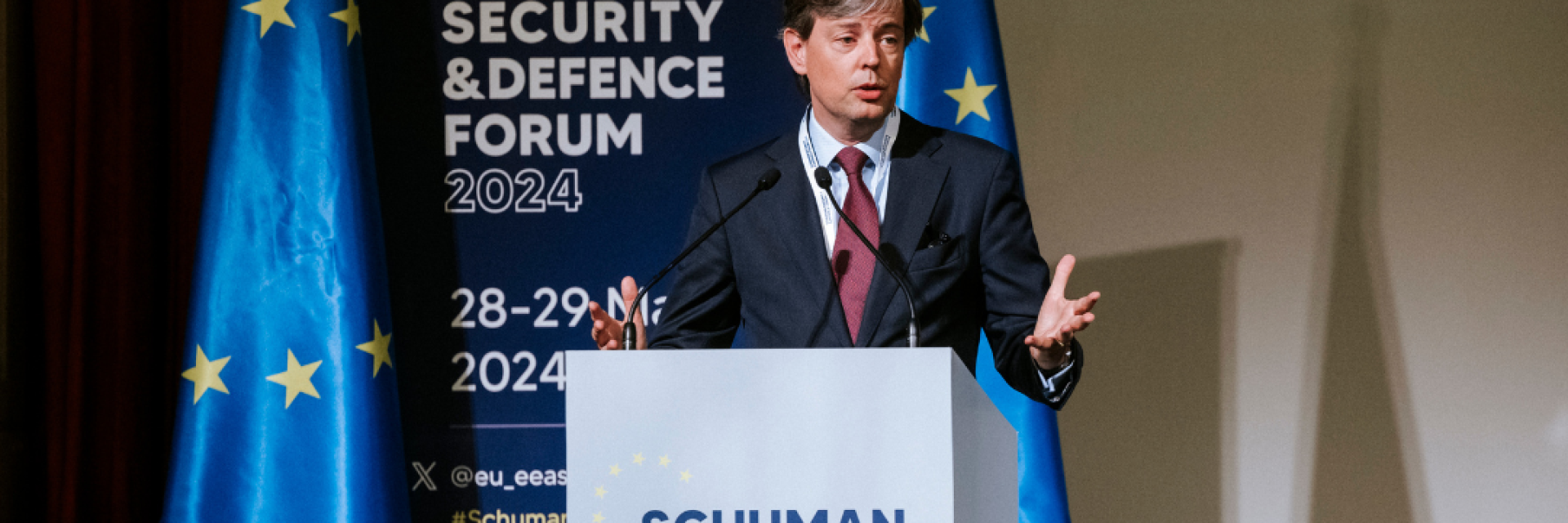 Director Steven Everts speaking on stage in from of banner with name of the event