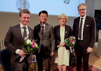 Panelists (three men and one women) posing for photo with bouquet of flowers © UI
