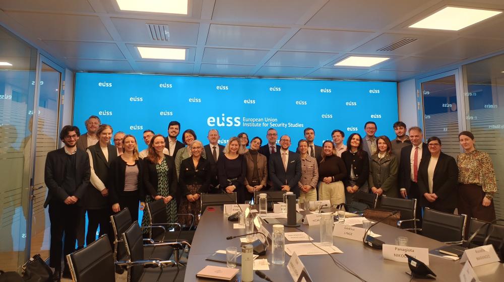 Group posing for photo in a meeting room in front of a background with EUISS logo. Credit photo: EUISS