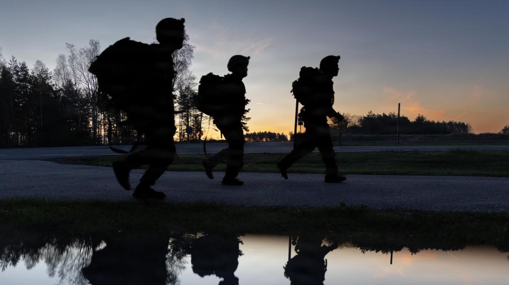 Silhouettes of soldiers walking as sun is setting. Credit photo: Army Pfc. Kadence Connors, US department of war. The appearance of US Department of War visual information does not imply or constitute DoW endorsement