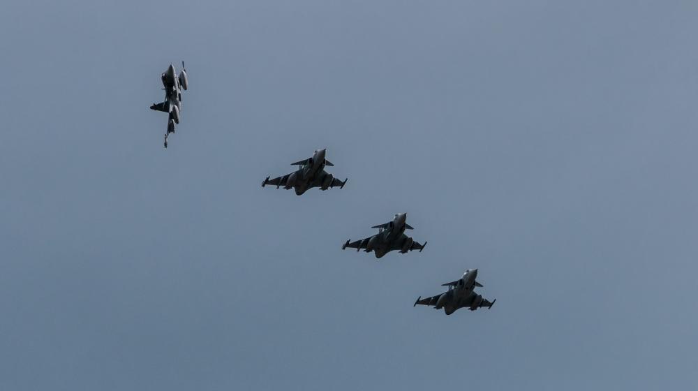 Four military jets are flying in formation against a clear blue sky. Image credit to NATO on Flickr.