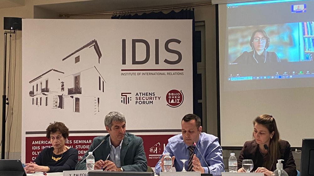 Panel members sitting at tables with microphones 