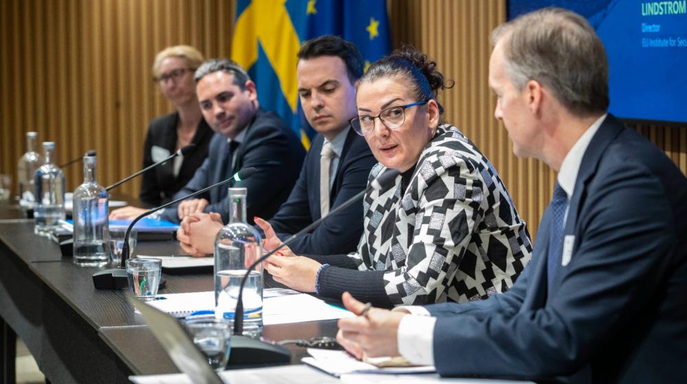 Panel members on a stage with background displaying the theme of the seminar ©EUISS