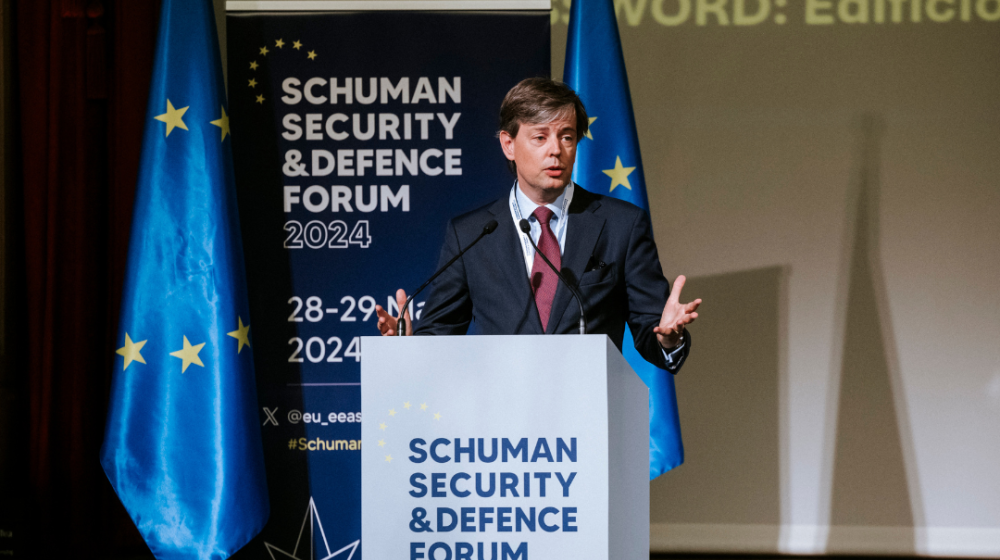 Director Steven Everts speaking on stage in from of banner with name of the event