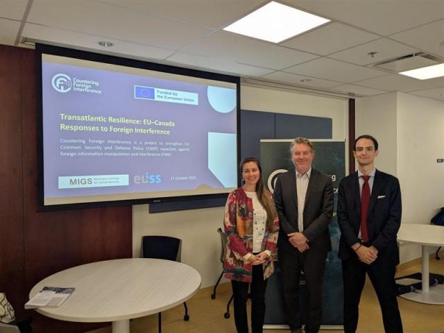 3 participants to the roundtable standing in front of screen with title of discussion. Credit photo: JULIAN HABER-MIGS